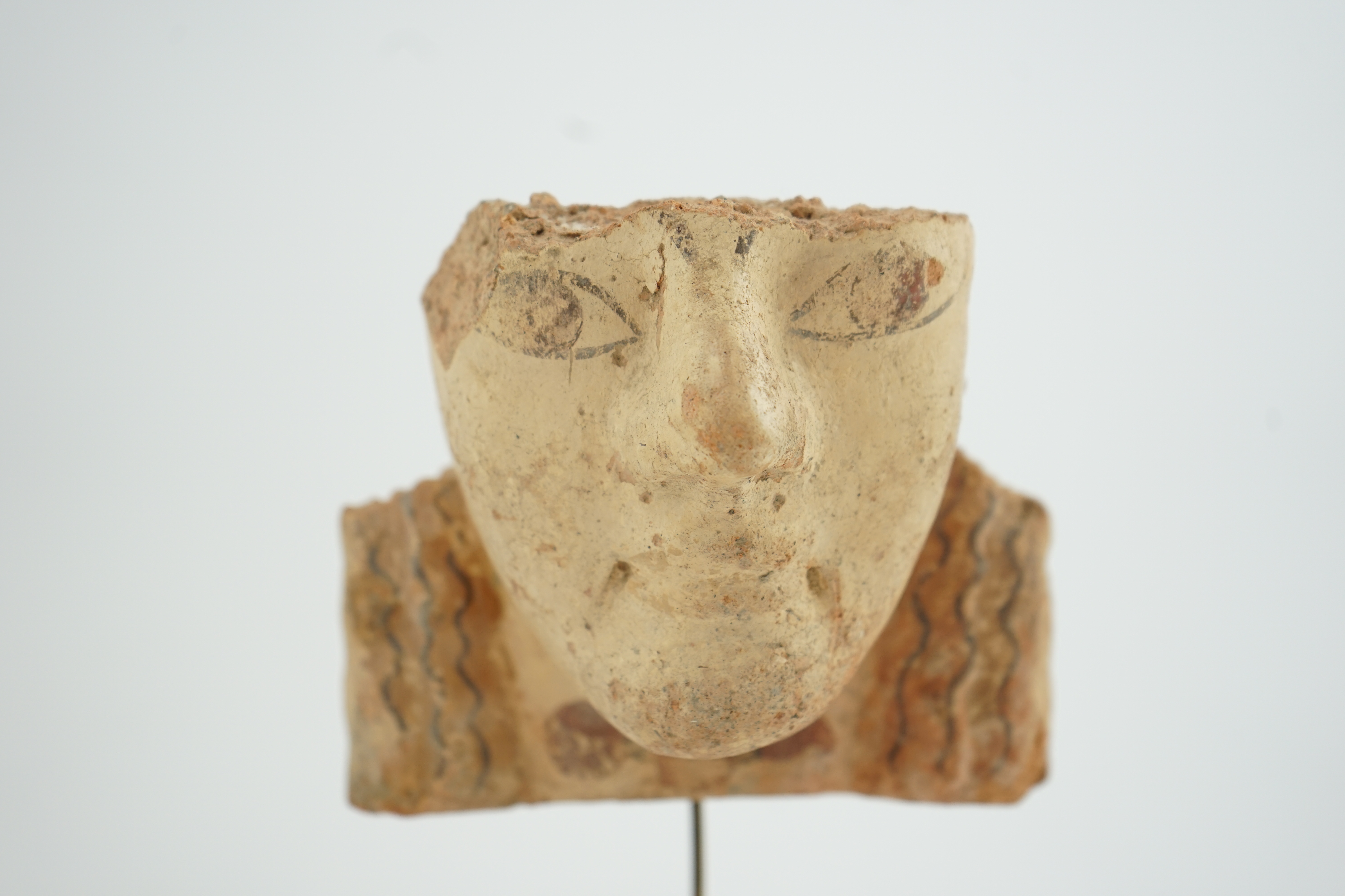 An Etruscan terracotta antefix, modelled as a head with polychrome painted features, 6th-5th century BC.